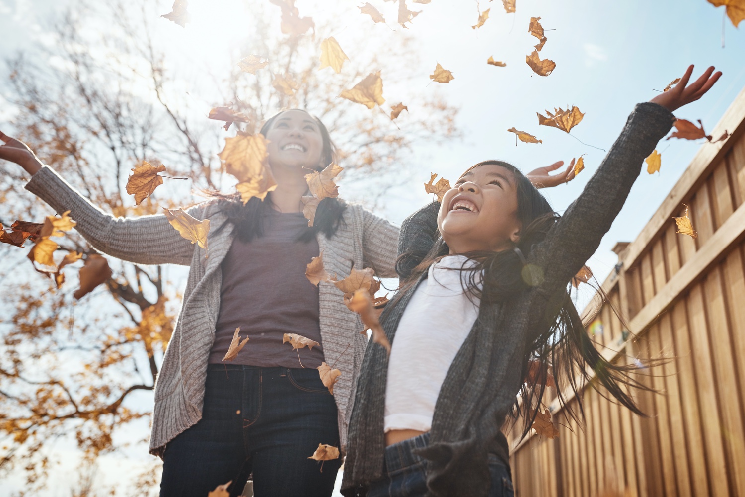 Mother and daughter playing in Autumn leaves